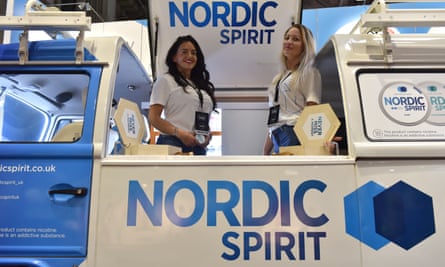 Two smiling young women in a converted open-top camper van painted in blue and white Nordic Spirit livery with logos
